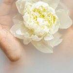 Allergy-Sensitive - Unrecognizable female with soft manicured hands holding white flower with delicate petals in hands during spa procedures